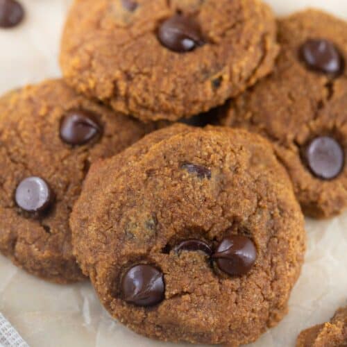 close up shot of paleo pumpkin cookies with chocolate chips, cooling on parchment paper