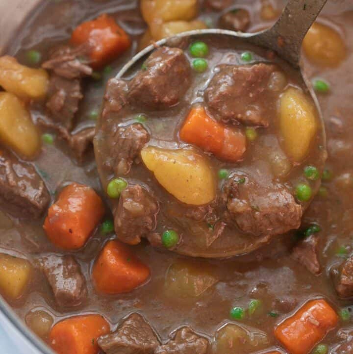 beef stew in pot being scooped with silver ladle