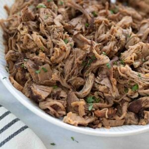 slow cooker pork in white bowl with silver spoon