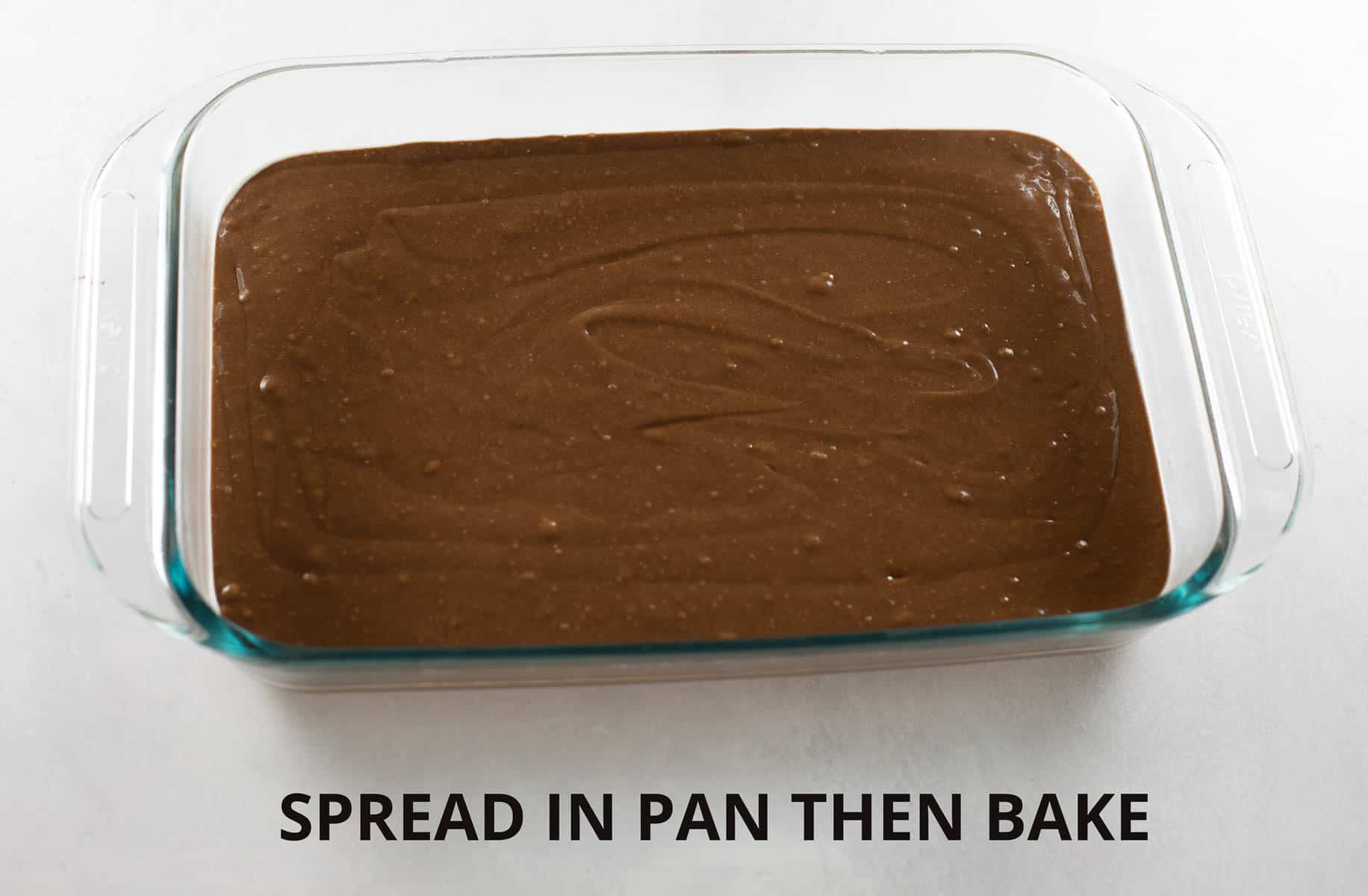 chocolate cake batter in glass pan before baking