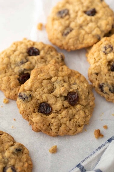 close up shot of gluten free oatmeal raisin cookies on white background with blue and white napkin