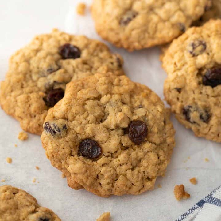 close up shot of gluten free oatmeal raisin cookies on white background with blue and white napkin