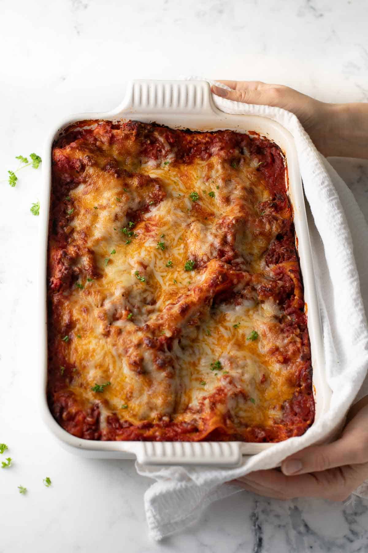 lasagna coming out of the oven with white cloth on marble background
