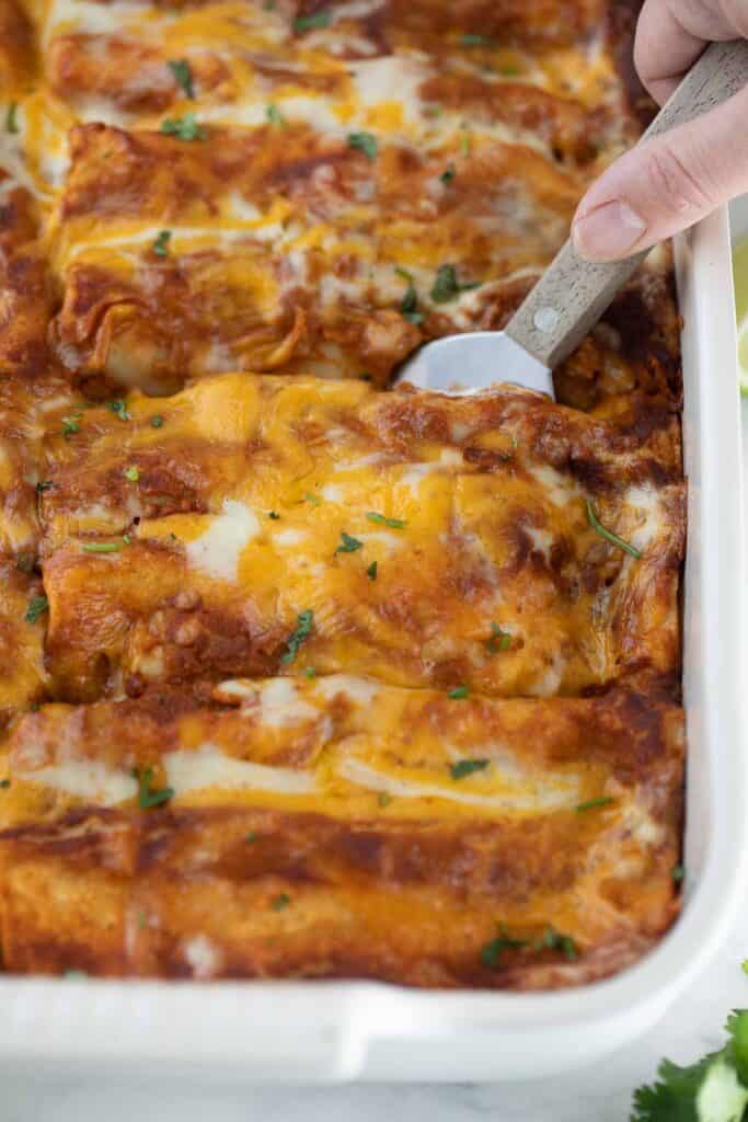 gluten free enchiladas in baking dish being scooped out with spatula