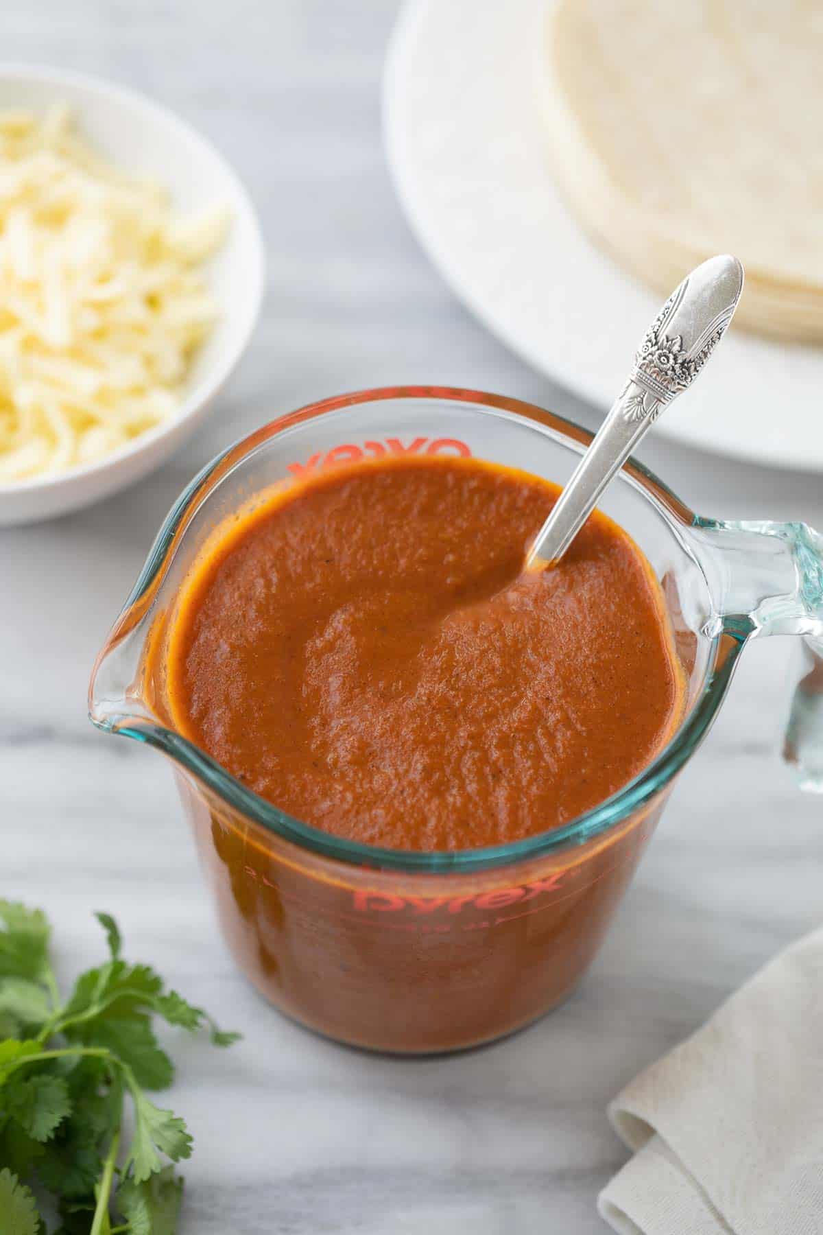 gluten free enchilada sauce in glass measuring cup with spoon