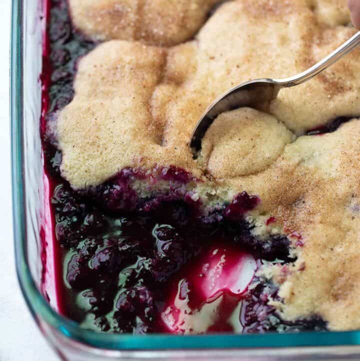 gluten free cobbler being scooped out of glass baking dish