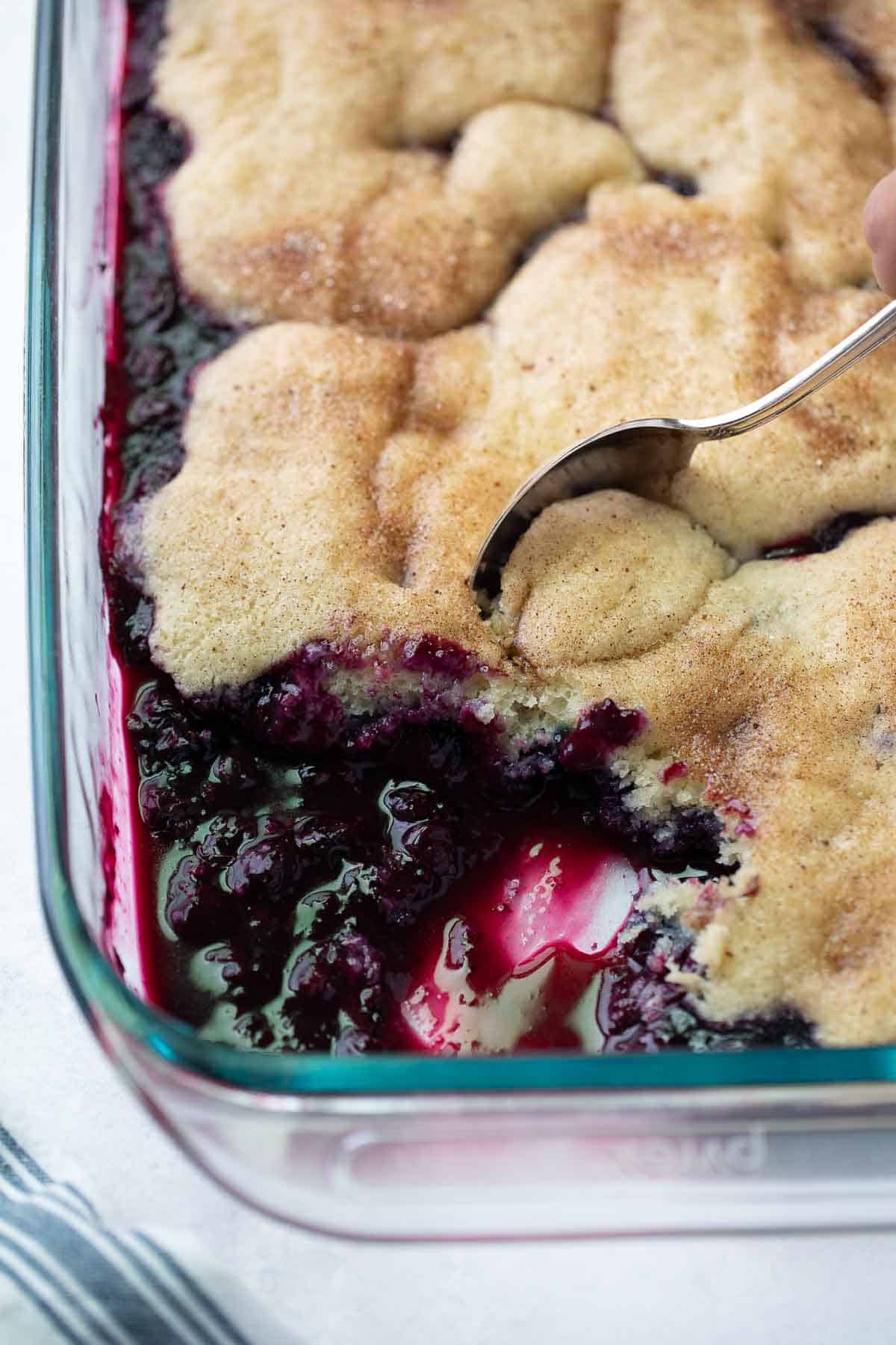 gluten free cobbler being scooped out of glass baking dish