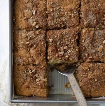 close up shot of gluten free coffee cake in metal baking dish with piece scooped out