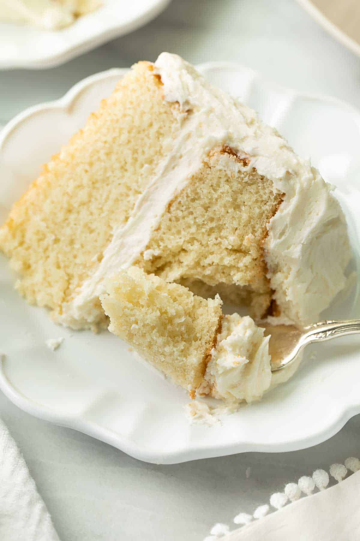 slice of gluten free cake on white plate with fork taking bite