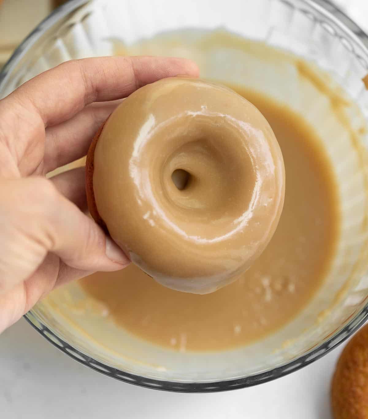 gluten free donut being dipped in glaze