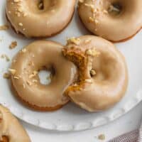 gluten free pumpkin donuts on white plate topped with walnuts
