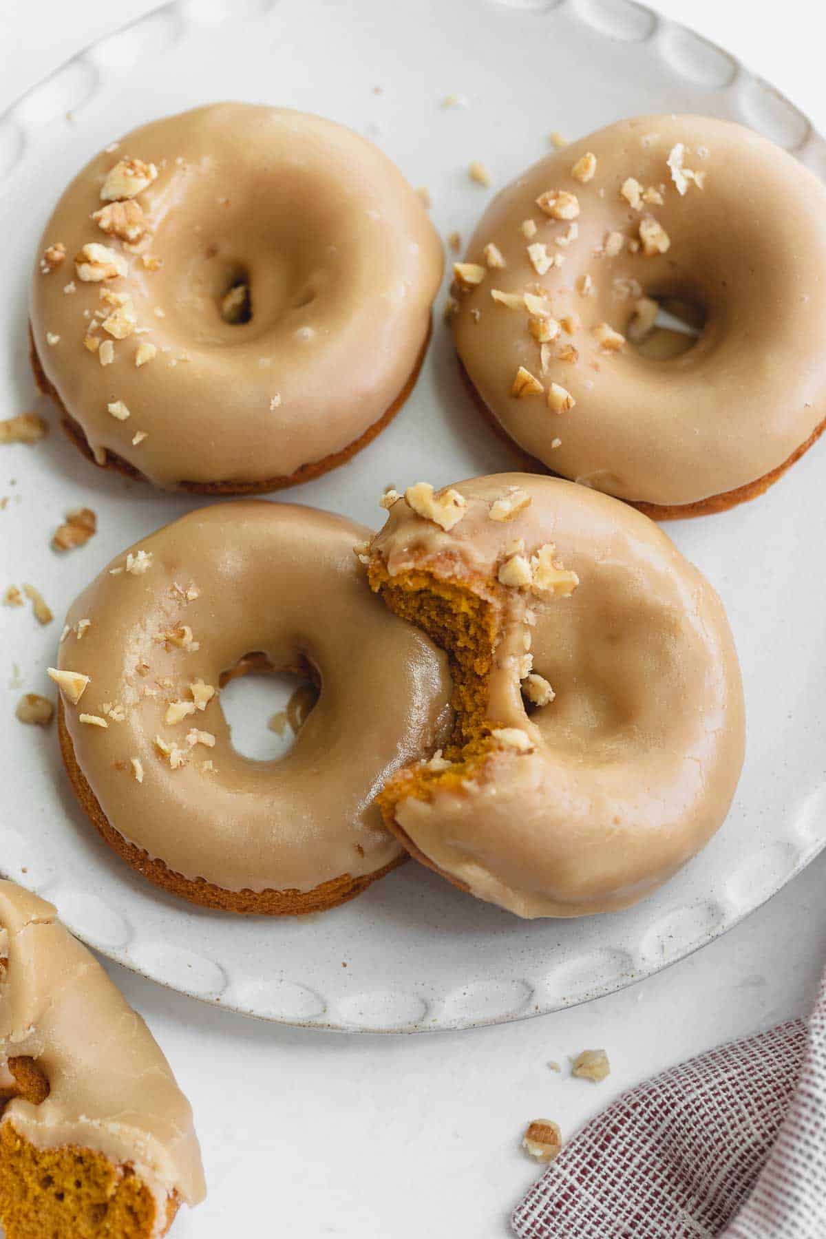 gluten free pumpkin donuts on white plate topped with walnuts