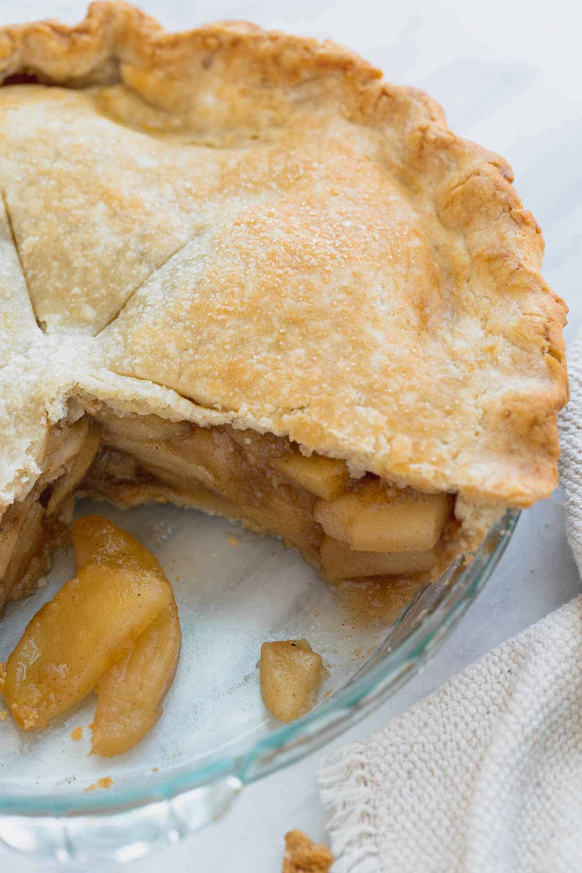 close up of apple pie in pan with slice cut out