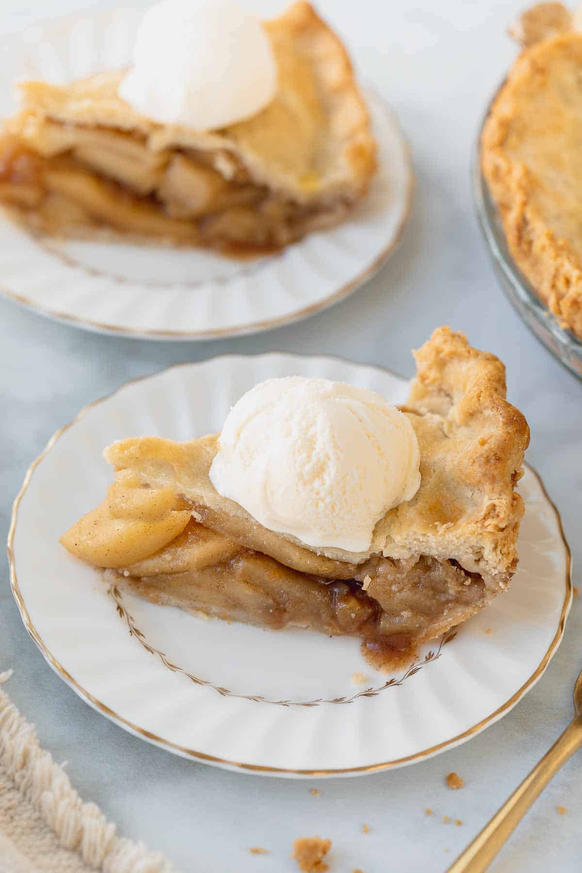 gluten-free apple pie slice on white plate topped with ice cream