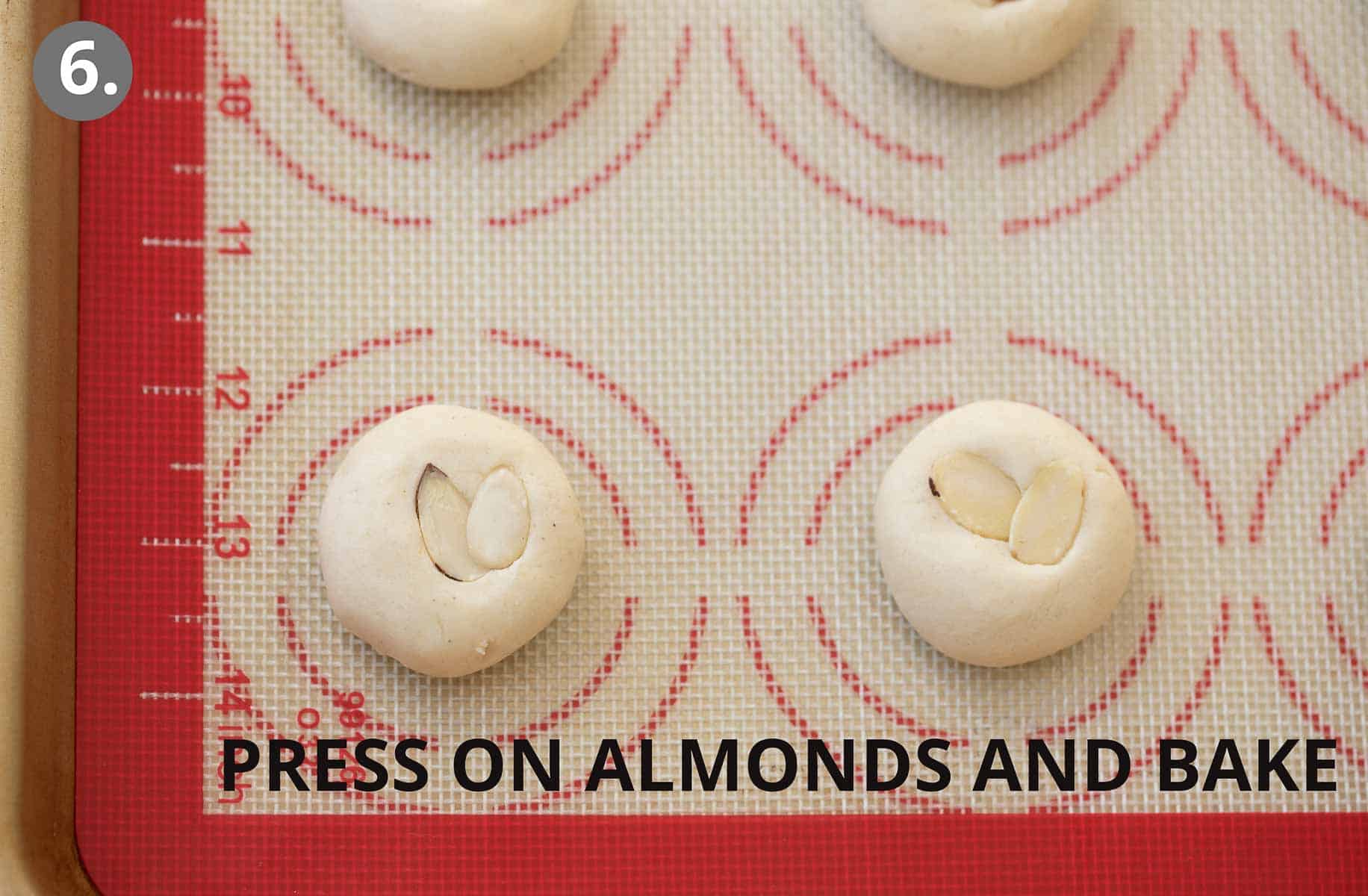 almonds pressed into dough balls on baking sheet