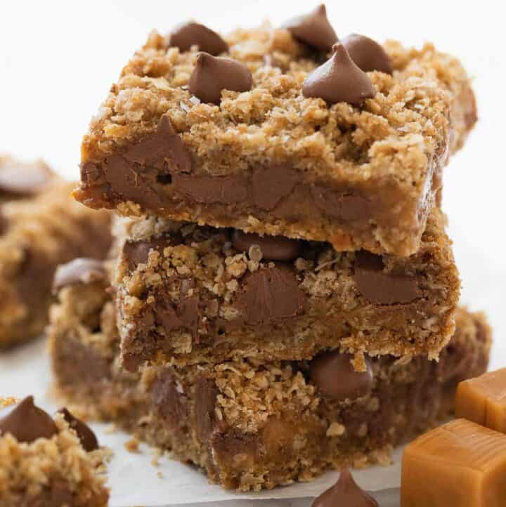 stack of gluten free oatmeal cookie bars with chocolate and caramel on white marble background