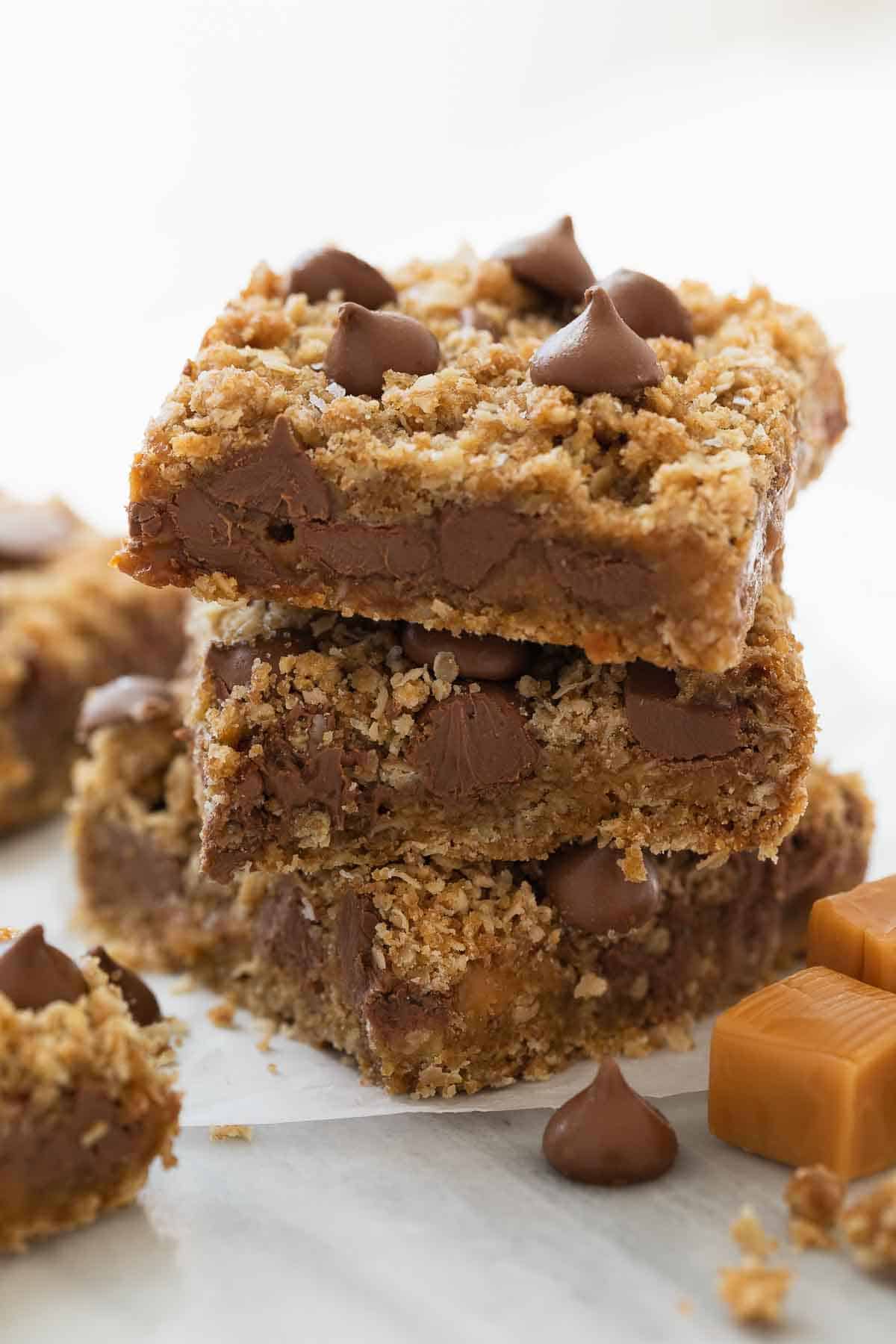 stack of gluten free oatmeal cookie bars with chocolate and caramel on white marble background