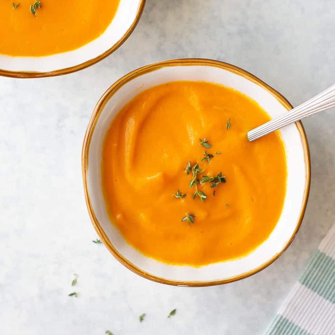 overhead shot of carrot soup in bowl topped with thyme