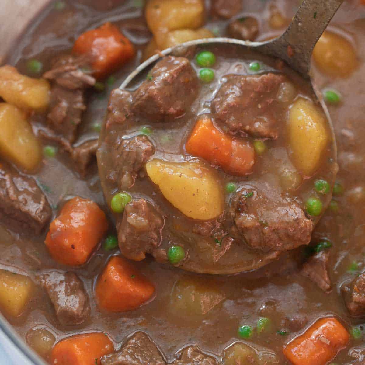 close up shot of beef stew in pot being scooped with ladle