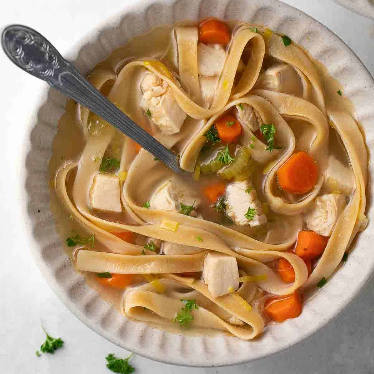 gluten free chicken noodle soup in bowl topped with thyme