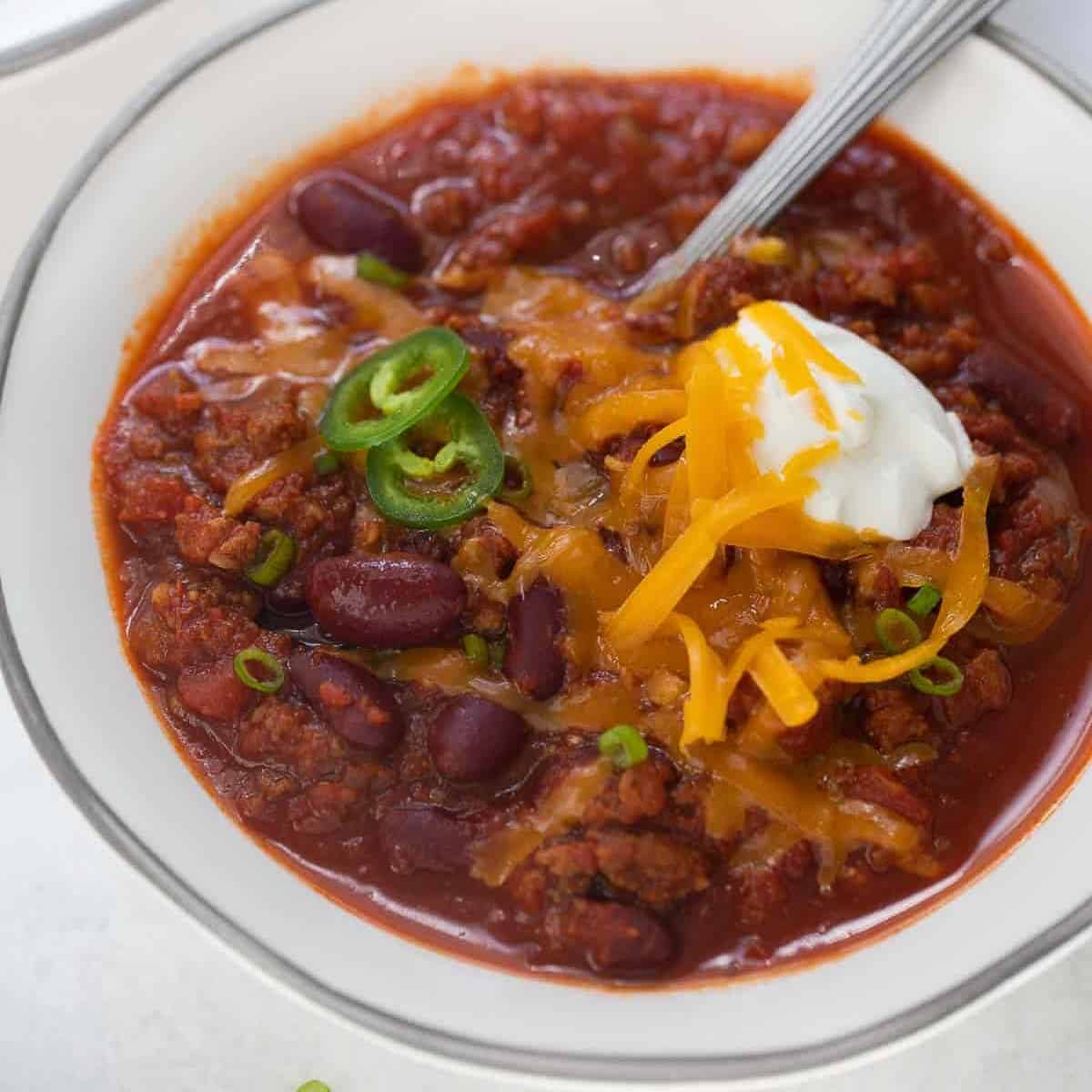 gluten free chili in bowl topped with cheese and jalapenos