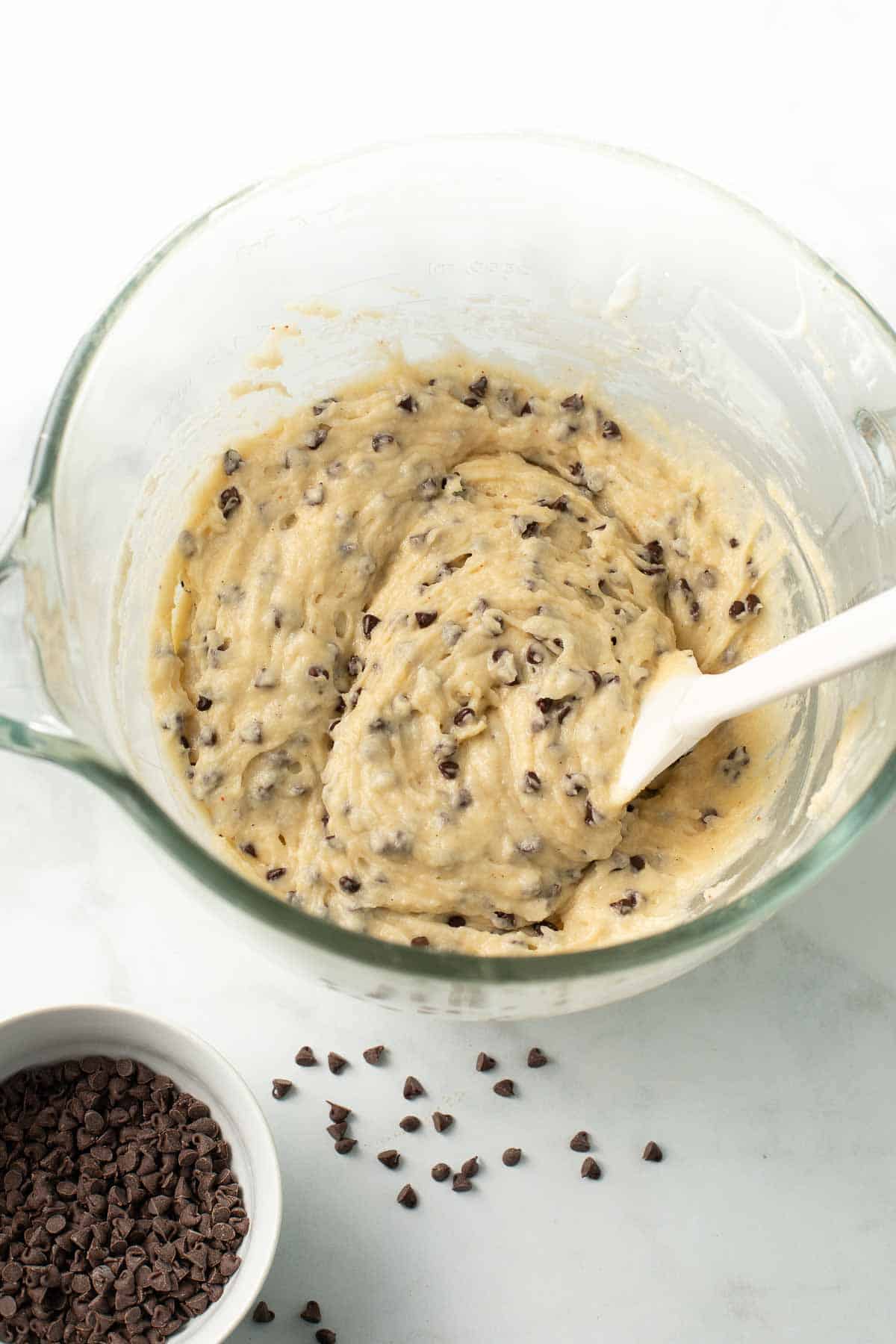 Chocolate chip muffin batter in a mixing bowl with a spatula