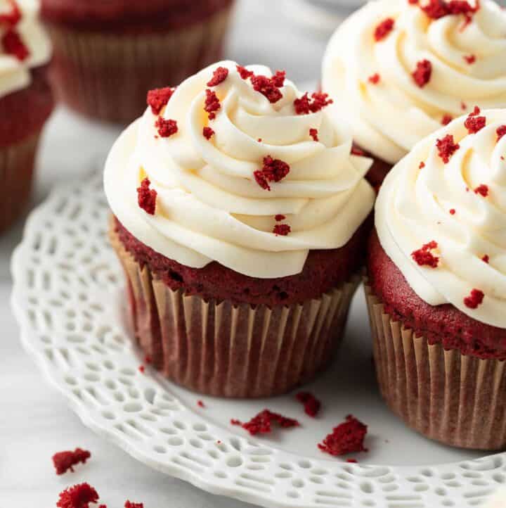 gluten free red velvet cupakes on white plate topped with cake crumbs