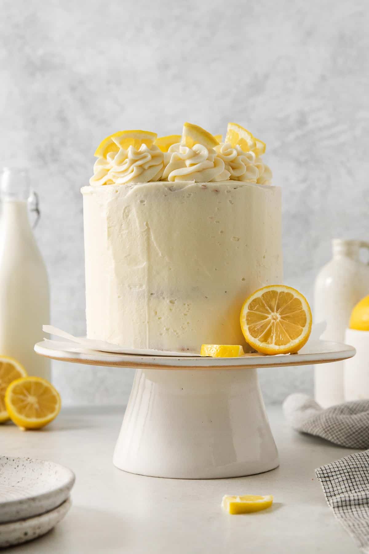 Gluten-free lemon cake on a cake stand with lemons on top and on the side