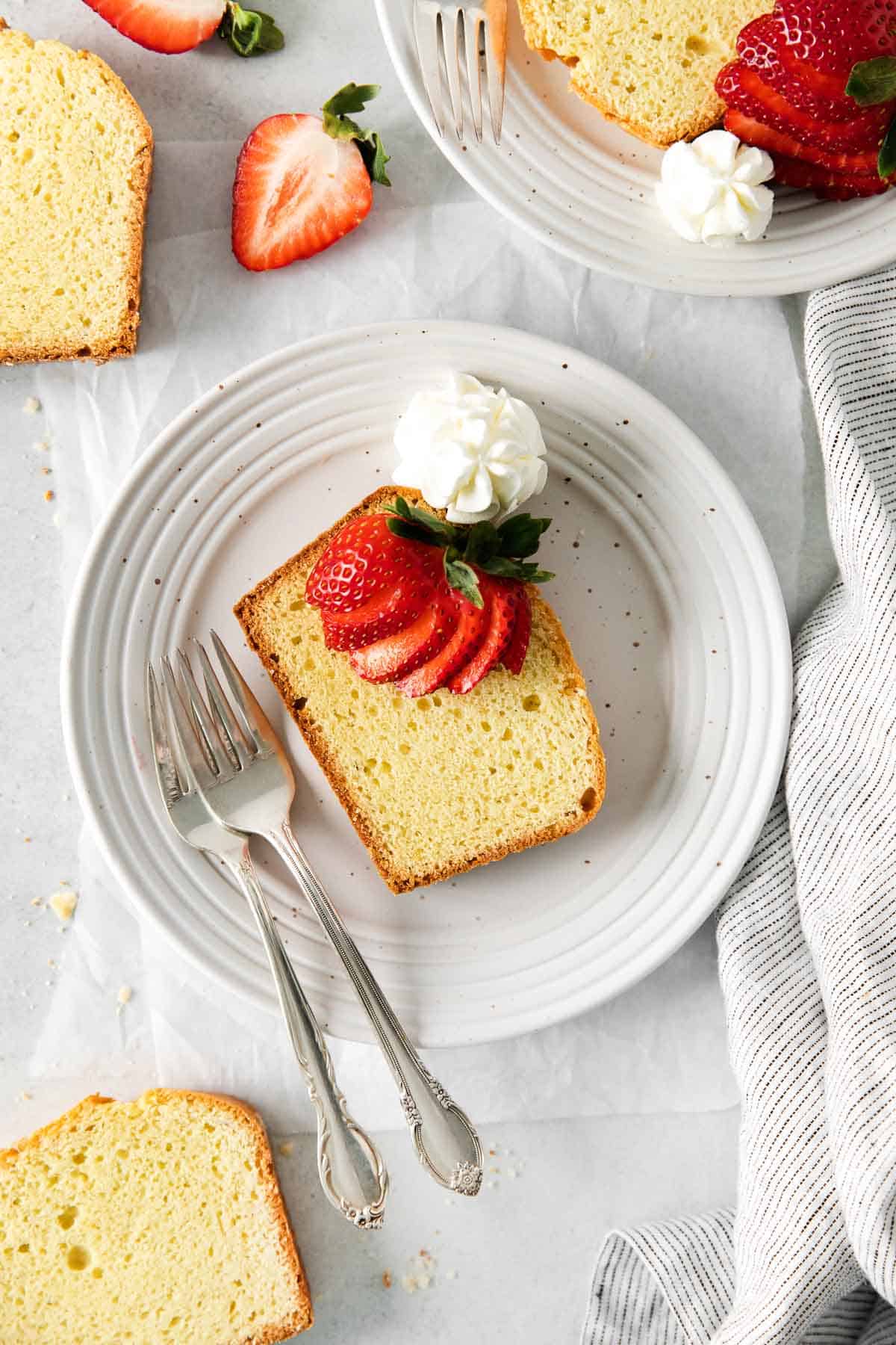 A slice of cake on a plate, topped with strawberries and cream