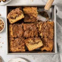sliced coffee cake in the baking pan with two slices turned to show the inside crumb.