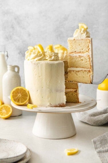 A slice of lemon cake being taken out of the cake on a cake stand