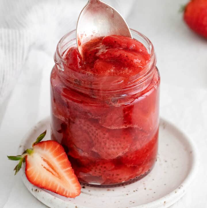 A closeup of strawberry compote in a glass jar