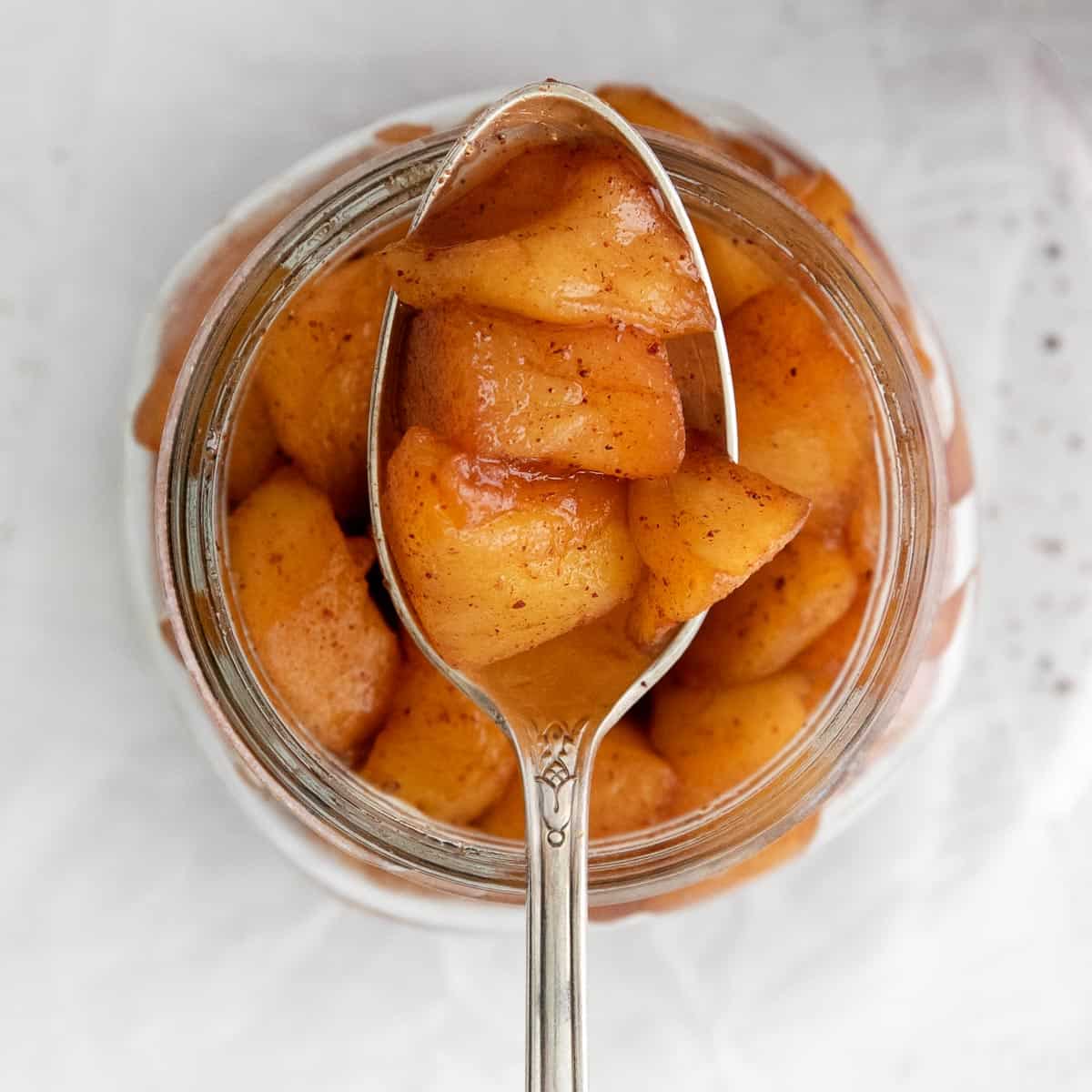 A spoonful of apple compote over a jar of compote