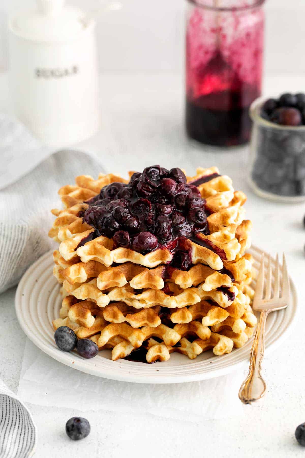 A stack of waffles on a plate, with blueberry compote on top