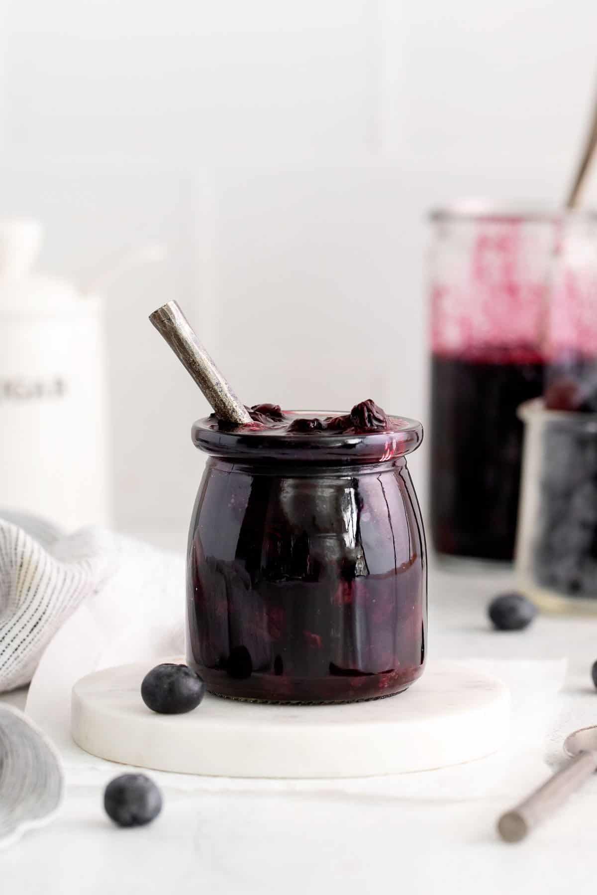 Blueberry compote in a jar, surrounded by cooking supplies