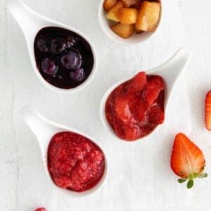 Four types of fruit compote arranged in ladles on a countertop