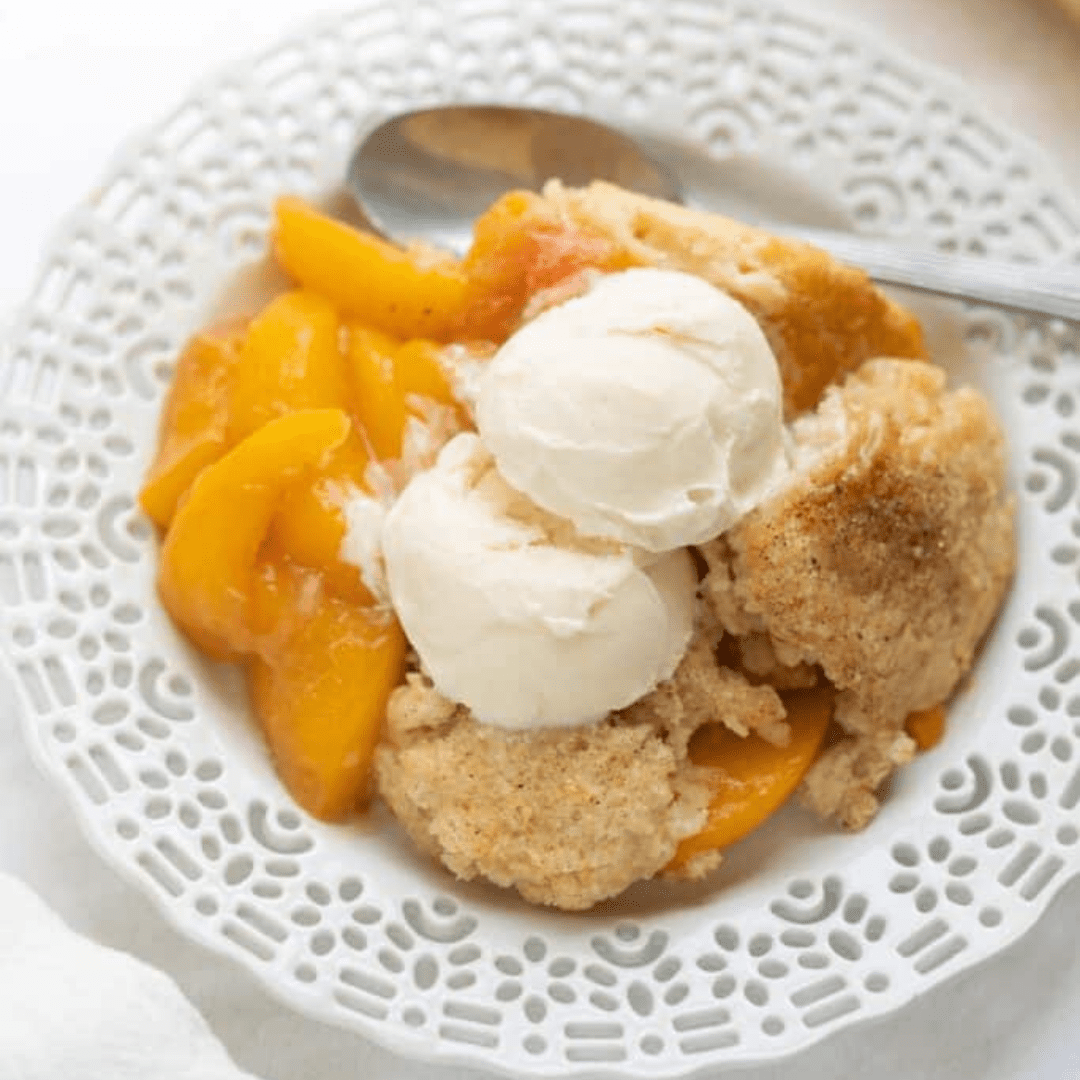 Peach cobbler in a bowl, with ice cream on top