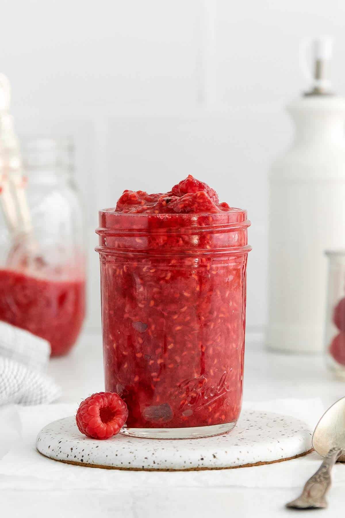 Raspberry compote in a mason jar on a countertop