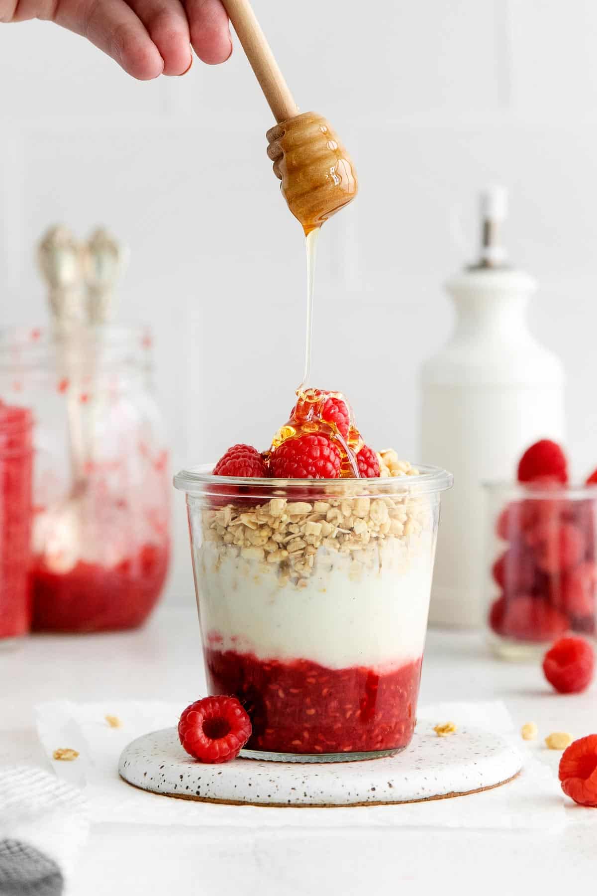Raspberry compote layered in a jar with yogurt, granola, and fresh raspberries