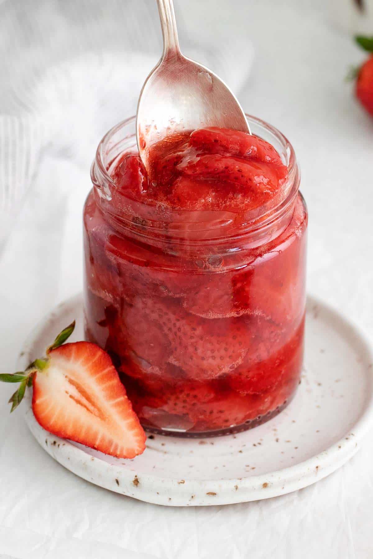 A closeup of strawberry compote in a glass jar