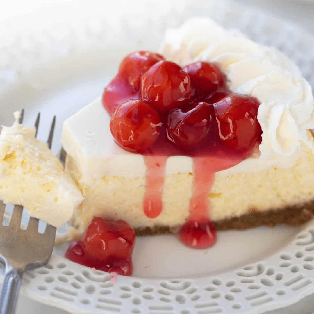A slice of cheesecake with cherries on top