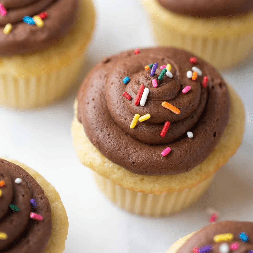 Cupcakes with chocolate frosting and sprinkles on a countertop