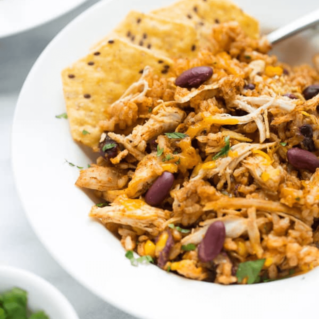 Shredded Southwest chicken in a bowl with chips and toppings