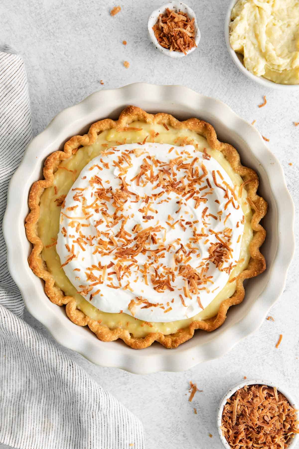 Dairy-free coconut cream pie surrounded by coconut shreds and cream in a bowl