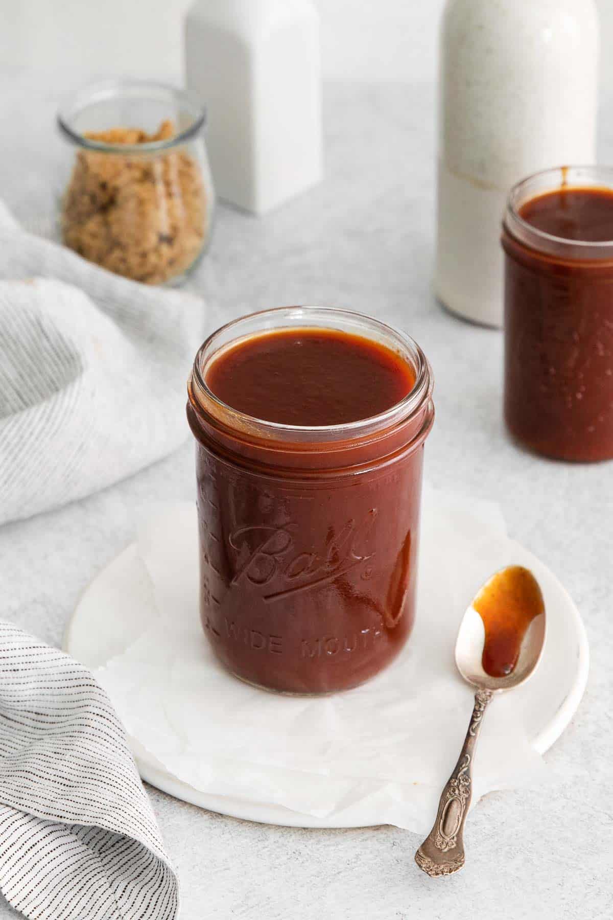 Gluten-free BBQ sauce in a glass jar, with a spoon next to it