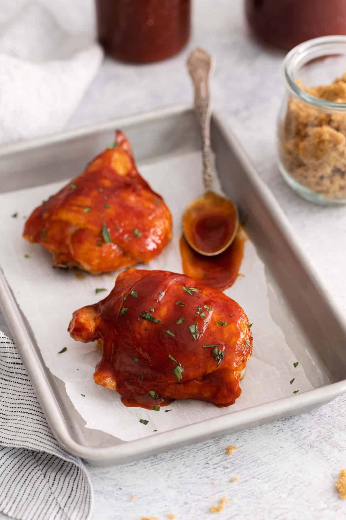 Gluten-free BBQ sauce spread over chicken on a baking sheet