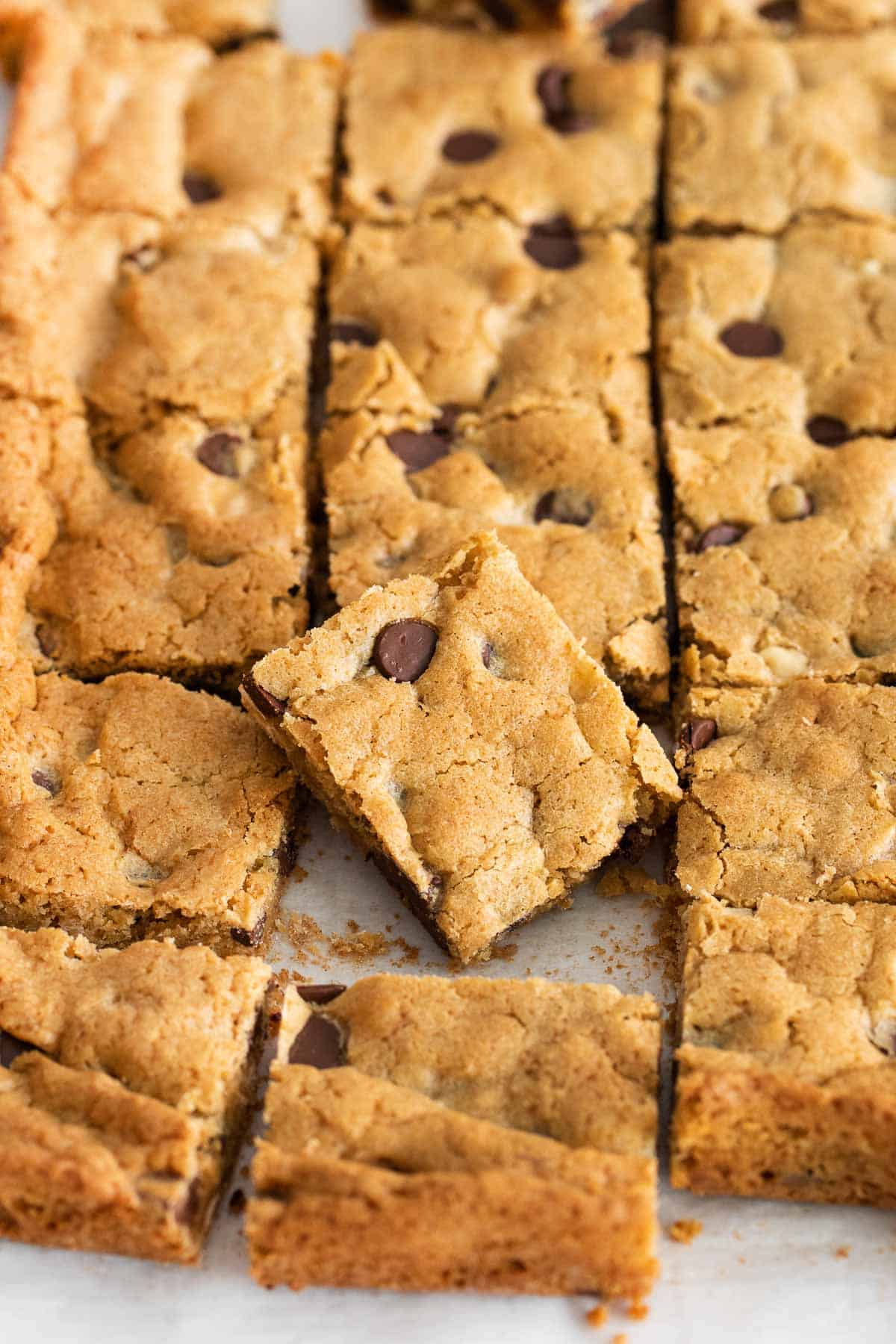 A close up of blondies sliced in a sheet pan, with one piece placed on top of the others