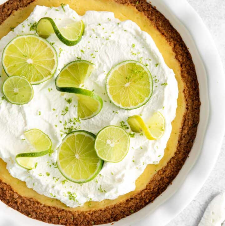 An overhead view of key lime pie with fresh limes on top