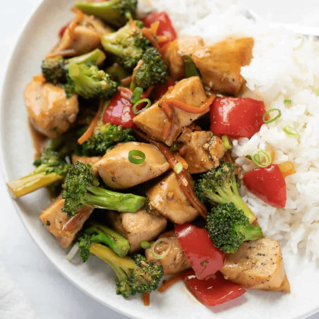 Stir fry chicken next to rice on a plate