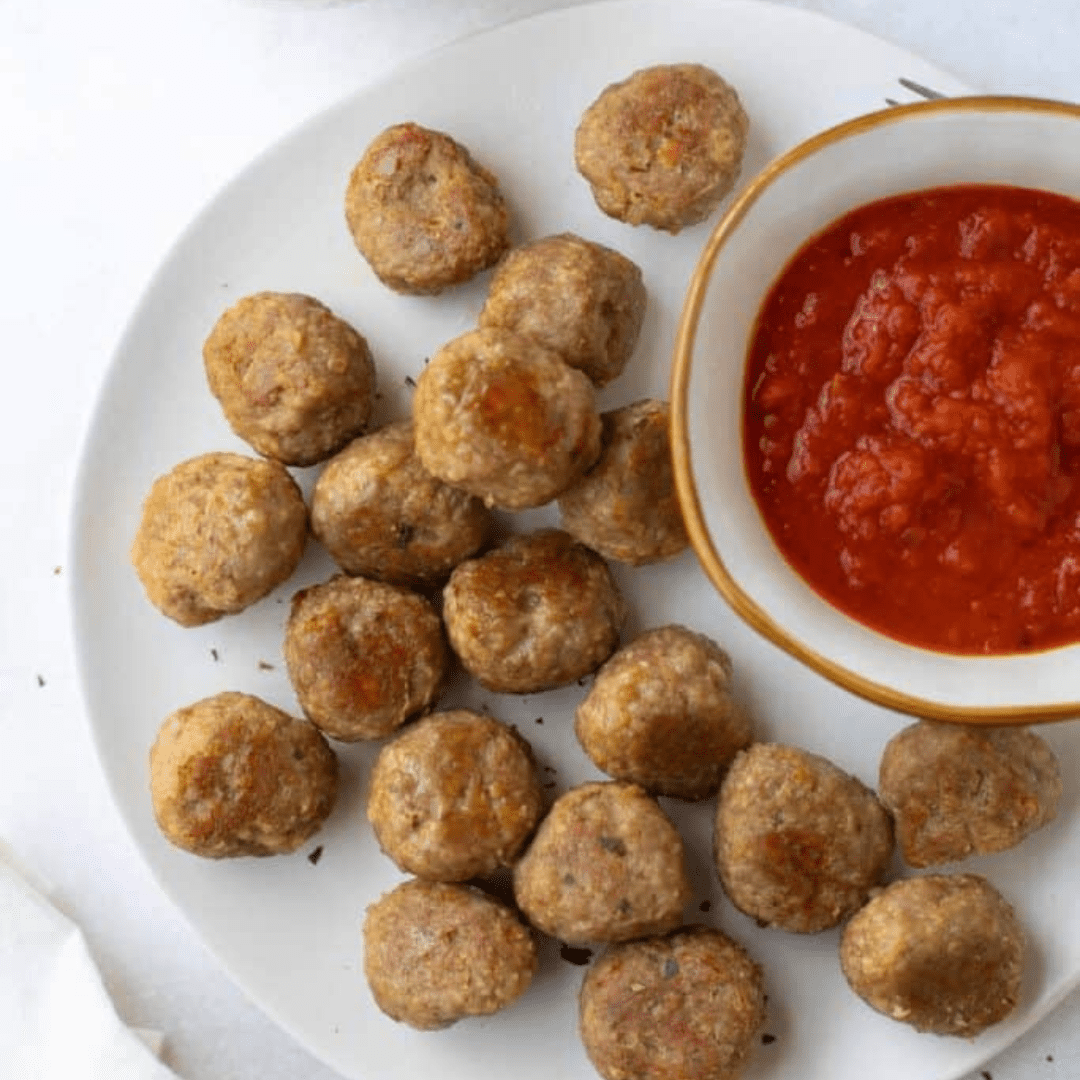 Turkey meatballs on a plate next to red sauce